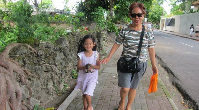 Angeline bersama dengan ibu angkatnya Margriet sedang berjalan kaki di Bali. Angeline terlihat sedang membawa anak kucing. Foto ini diberi keterangan bahwa Angeline menemukan anak kucing yang terlantar. (Facebook.com/Find Angeline - Bali's Missing Child)