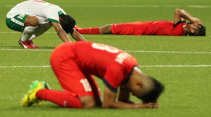 Ekspresi bersyukur Zulfiandi kontras dengan ekspresi kesedihan dua pemain Singapura U-23 di SEA Games 2015. (Bola.com/Arief Bagus)