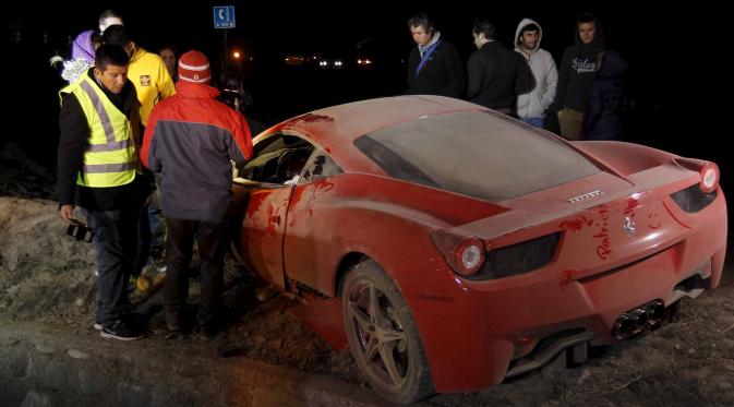 Sejumlah warga melihat kondisi mobil ferrari milik Arturo Vidal yang rusak parah usai mengalami kecelakaan di Kota Buin, Chile, Selasa (16/6/2015). Arturo Vidal mengalami luka ringan dan langsung dibawa ke rumah sakit. (REUTERS/Felipe Fredes)