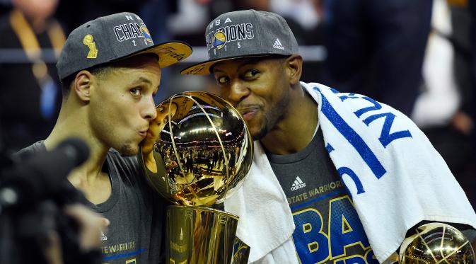 Stephen Curry (kiri) dan Andre Iguodala mencium trofi usai mengalahkan Cleveland Cavaliers di pertandingan ke enam final NBA di Quicken Loans Arena, (17/6/2015). Warriors menang 105-97 pada pertandingan ke enam final NBA. (Reuters/Bob Donnan)