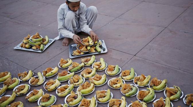 Seorang anak Muslim bersiap untuk mendistribusikan makanan Iftar selama bulan suci Ramadhan di Masjid Jama di kuartal tua Delhi, India.