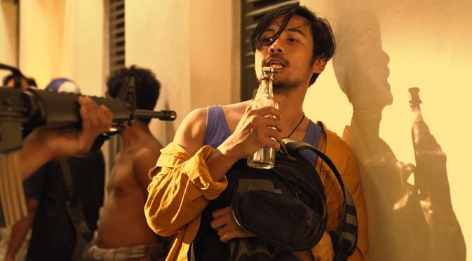 Chico Jerikho memegang botol minuman jadul di sebuah adegan film Aach... Aku Jatuh Cinta. Foto: MVP Pictures