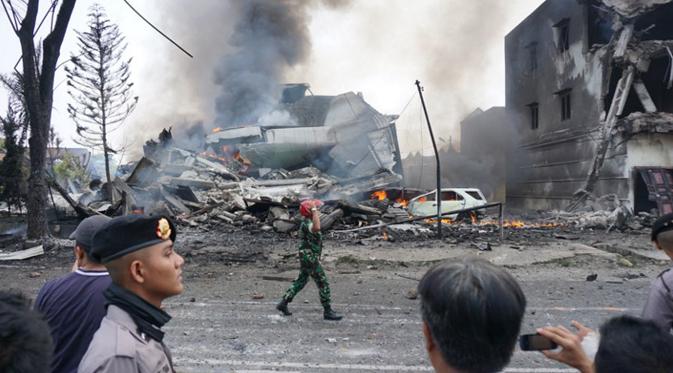 Petugas saat mengamankan lokasia kecelakaan pesawat Hercules C-130 yang jatuh di kawasan perumahan di Medan, Selasa (30/6/2015). Hercules C-130 milik TNI AU jatuh tidak lama setelah lepas landas. (AFP PHOTO/Muhammad Zulfan Dalimunthe)