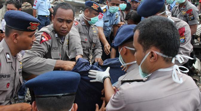 Petugas kepolisian mengevakuasi korban jatuhnya pesawat Hercules C-130 yang jatuh di kawasan perumahan di Medan, Selasa (30/6/2015). Hercules C-130 milik TNI AU jatuh tidak lama setelah lepas landas. (AFP PHOTO/ATAR)