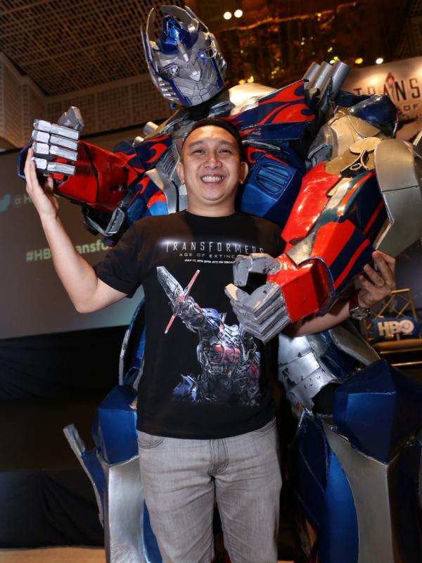 Augie Fantinus ceria berpose bersama Optimus Prime, salah satu tokoh Transformers (Galih W Satria/Bintang.com)