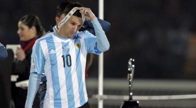 Lionel Messi melepas medali perak yang diraihnya. (AFP PHOTO/JUAN MABROMATA)