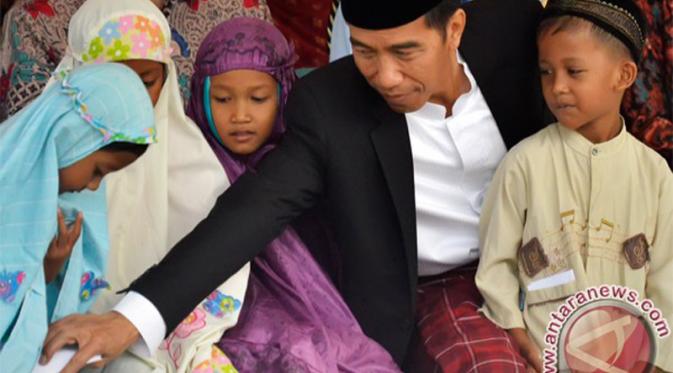 Presiden Jokowi membagikan uang Lebaran kepada anak-anak saat bersilaturahmi dengan warga di Kampung Punge, Kecamatan Jaya Baru, Banda Aceh, Jumat (17/7/2015). (Antara/Yudhi Mahatma)