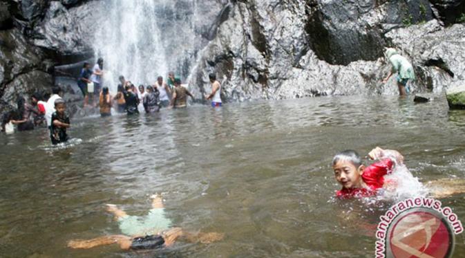 Pengunjung mandi di bawah air terjun Sedudo, Nganjuk, Jawa Timur. (Antara Foto/Rudi Mulya)