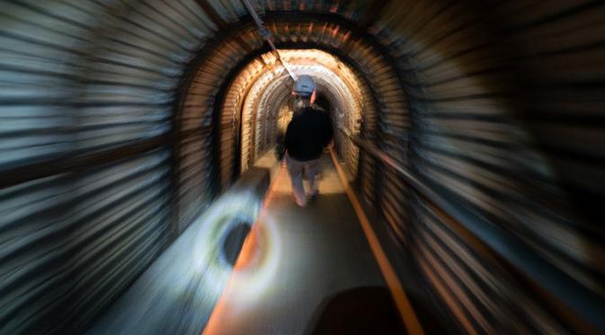 Seorang pria menuruni 125 anak tangga saat menelusuri terowongan Fan Bay Deep Shelter, tepat di bawah White Cliffs of Dover, Inggris, Kamis (23/7/2015). Terowongan ini diciptakan oleh Perdana Menteri Inggris Winston Churchill 1940. (AFP/Leon Neal)
