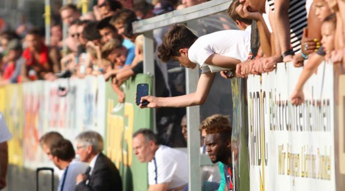  DEMI SELFIE – Seorang fans mencoba untuk mendapatkan foto pemain PSG yang tengah duduk di bangku cadangan tim. (Bola.com/Reza Khomaini)