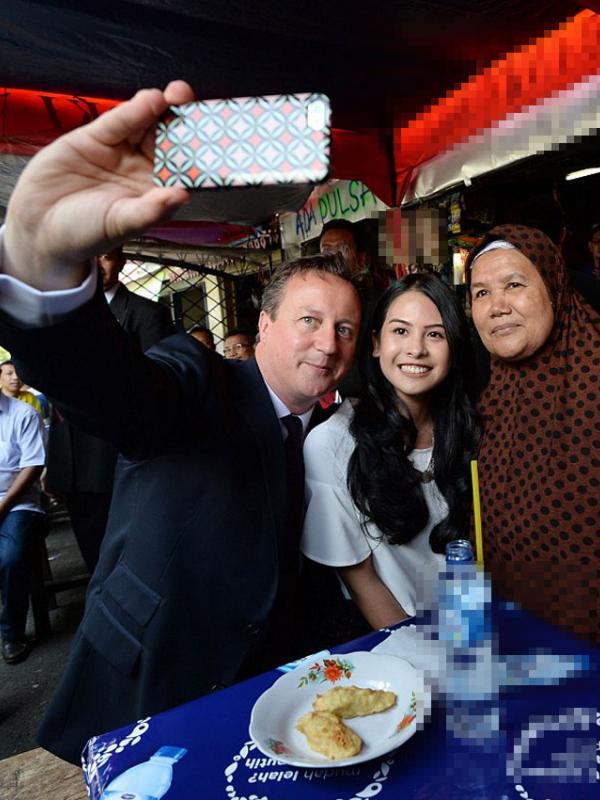 Dalam kunjungannya, David Cameron ditemani penyanyi cantik Maudy Ayunda. Mereka melakukan foto selfie bersama ibu pemilik warung. (via dailymail.co.uk)