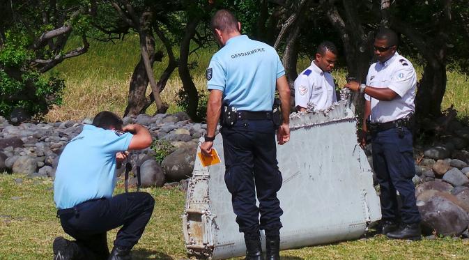 Polisi berdiri dekat potongan mirip badan pesawat di pantai Saint - Andre, Perancis, Rabu  (29/30/2015). Lembaga investigasi Perancis akan berkoordinasi dengan pemerintah Malaysia dan Australia apa itu dari Malaysia Airlines MH370. (REUTERS/Prisca Bigot)