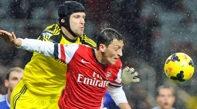 Kiper Chelsea, Petr Cech duel udara dengan gelandang Arsenal, Mesut Oezil pada laga Liga Inggris musim 2013/14 di Inggris, Senin (23/12/2013). Cech kini sudah berkostum Arsenal. (EPA/Gerry Penny)