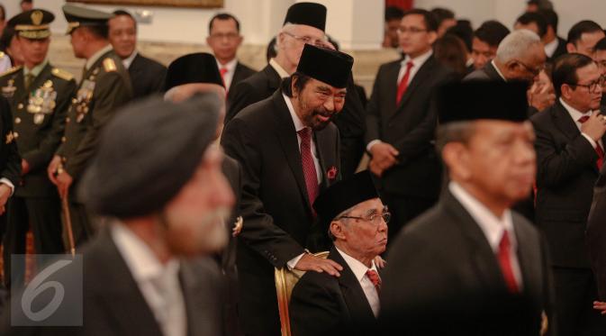 Tokoh Pers Nasional, Surya Paloh memegang pundak anggota DPR RI Fraksi PDI-P, Sabam Sirait saat acara pemberian tanda kehormatan oleh Presiden Jokowi kepada tokoh nasional di Istana Negara, Jakarta, Kamis (13/8). (Liputan6.com/Faizal Fanani)