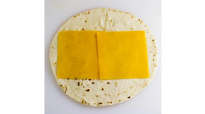 Letakkan keju lembaran di atas tortilla. (Via: homecookingmemories.com)