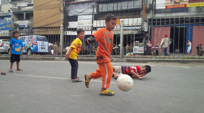 Bocah-bocah Kampung Pulo asyik bermain bola di jalan raya yang telah ditutup. (Liputan6.com/Osfar Ferri)