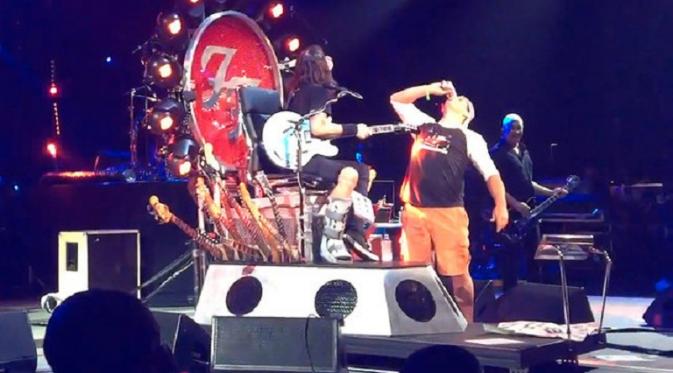 Dave Grohl dan seorang fansnya minum bir bareng di atas panggung (NME)