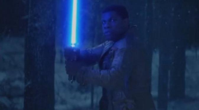 Karakter yang diperankan John Boyega, Finn, memegang lightsaber di hutan bersalju. dalam video teaser Star Wars: The Force Awakens. (Ace Showbiz)