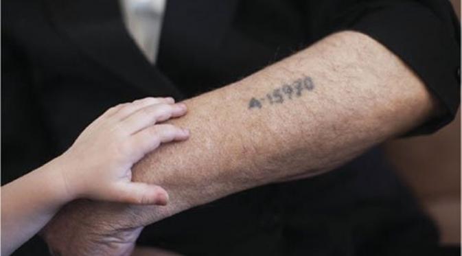 Seorang Yahudi yang berhasil selamat dari kamp konsentrasi menunjukkan tato nomor tahanan  yang dilakukan oleh Nazi 