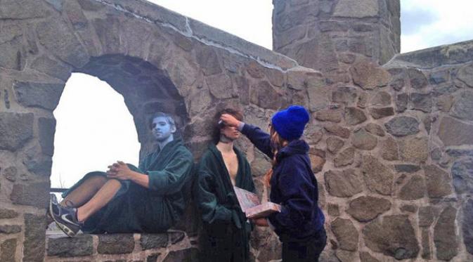 Natalie Fletcher, sang seniman mewarnai wajah si model dengan warna biru untuk nantinya disamarkan dalam dinding bebatuan.