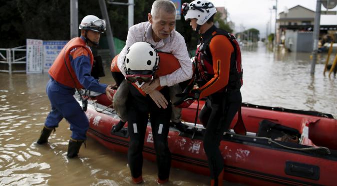 Punggung para petugas pun menjadi penyelamat warga yang terjebak banjir Jepang. (Reuters)