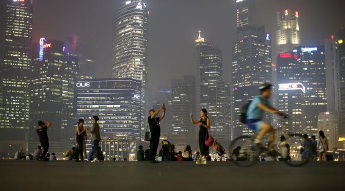 Turis-turis berfoto di Singapura, di tengah kabut asap (Reuters)