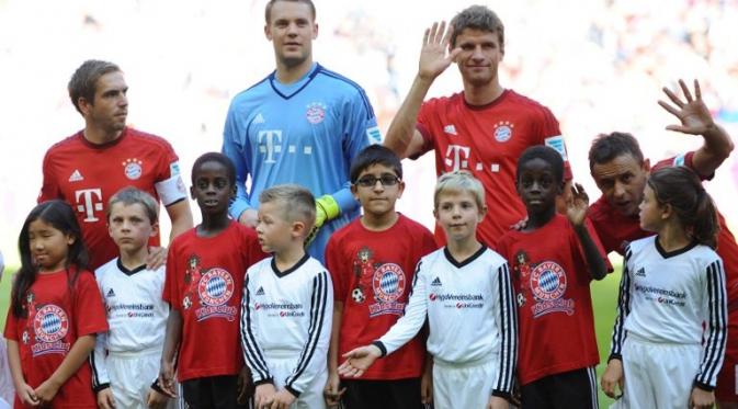 Pemain Bayern Muenchen Philipp Lahm, Manuel Neuer dan Thomas Mueller berfoto dengan anak-anak pengungsi (kaos merah) sebelum melawan FC Augsburg dalam lanjutan Liga Jerman. Sabtu (12/9/2015). (AFP Photo/DPA/Anandreas Gebert)
