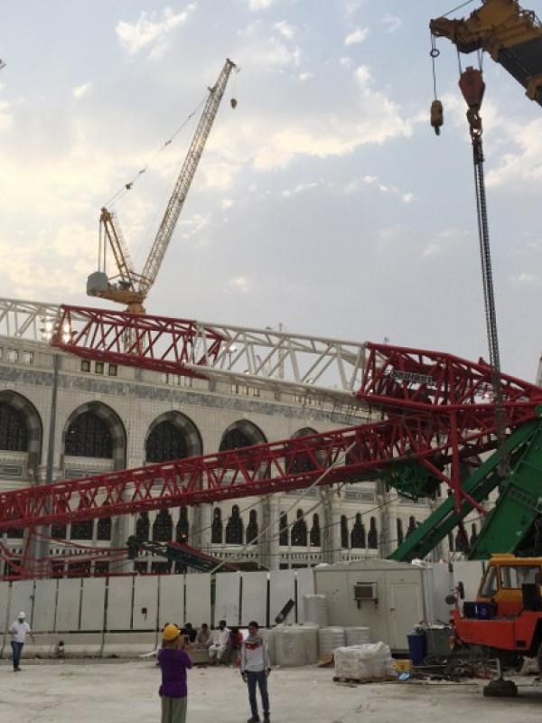 Pekerja dibantu alat berat berusaha mengevakuasi crane yang roboh di Masjidil  Haram, Kota Mekah,  Arab Saudi (9/12/2015). Sebanyak 107 calon jemaah haji meninggal dunia akibat crane jatuh karena cuaca buruk. (AFP PHOTO / STR)