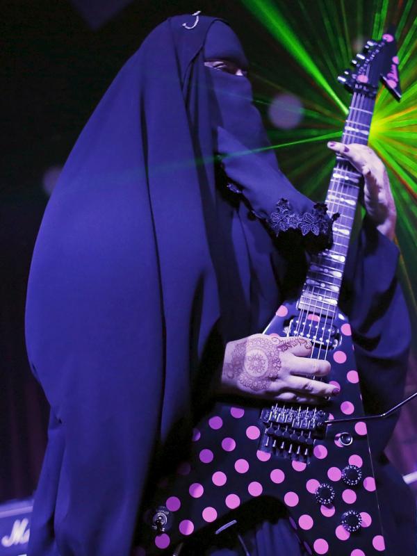 Musisi heavy metal Muslim wanita, Gisele Marie memainkan gitar listrik saat konser di Sao Paulo, Brasil (16/12/2014). Marie merupakan cucu dari kakek beragama Katolik Jerman, ia masuk Islam setelah ayahnya meninggal pada tahun 2009. (REUTERS/Nacho Doce)