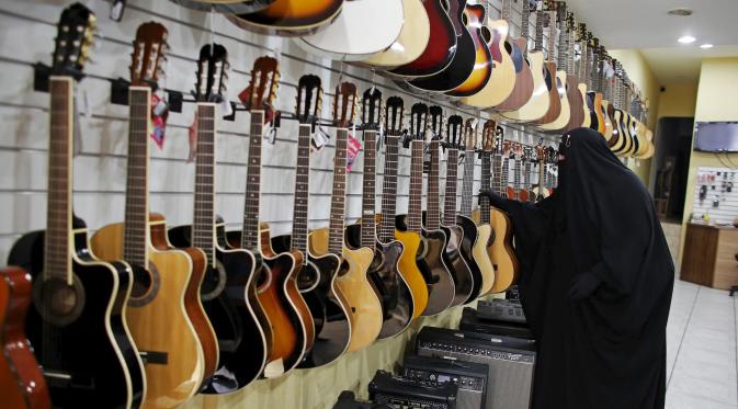 Gisele Marie melihat gitar di sebuah toko yang menjual alat musik di Sao Paulo, Brasil (13/8/2015). Marie merupakan cucu dari kakek beragama Katolik Jerman, ia masuk Islam setelah ayahnya meninggal pada tahun 2009. (REUTERS/Nacho Doce)