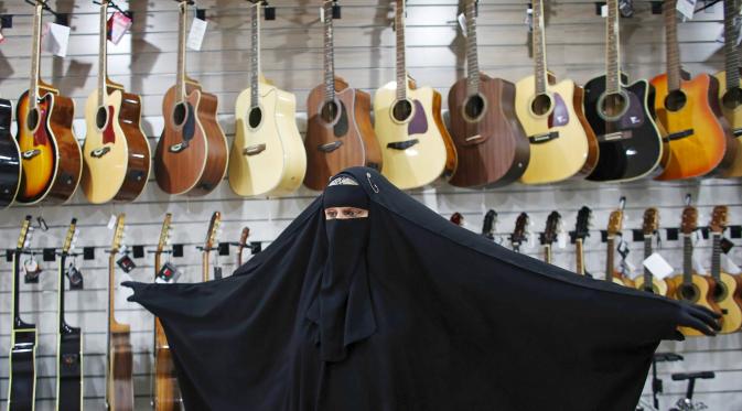 Gisele Marie mengerakan tubuhnya di depan gitar sebuah toko yang menjual alat musik di Sao Paulo, Brasil (13/8/2015). Marie merupakan cucu dari kakek beragama Katolik Jerman, ia masuk Islam setelah ayahnya meninggal pada tahun 2009. (REUTERS/Nacho Doce)