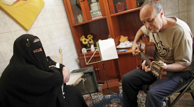 Gisele Marie melihat gurunya Marcelo (kanan) memainkan gitar selama kelas musik di Sao Paulo, Brasil (13/8/2015). Marie merupakan cucu dari kakek beragama Katolik Jerman, ia masuk Islam setelah ayahnya meninggal pada tahun 2009. (REUTERS/Nacho Doce)