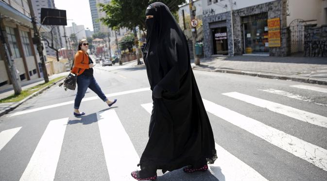 Gisele Marie melintasi jalan setelah latihan di sebuah studio, Sao Paulo (15/9/2015). Banyak orang disekitarnya terkejut melihat seorang wanita Muslim yang menggunakan Burka memainkan musik metal. (REUTERS/Nacho Doce)
