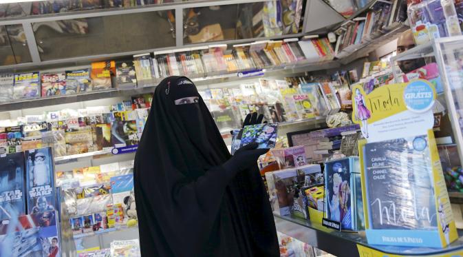 Gisele Marie memilih CD musik disebuah toko usai latihan sebuah studio, Sao Paulo, Brasill (15/9/2015). Banyak orang disekitarnya terkejut melihat seorang wanita Muslim yang menggunakan Burka memainkan musik metal. (REUTERS/Nacho Doce)