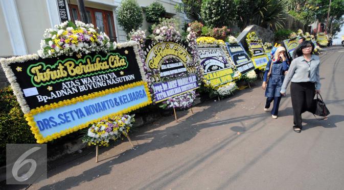 Warga melintas di depan Karangan bunga di rumah duka almarhum Adnan Buyung di kawasan Lebak Bulus, Jakarta, Rabu (23/9/2015). Adnan menghembuskan napas terakhir pada pagi tadi pukul 10.15 WIB. (Liputan6.com/Helmi Afandi)